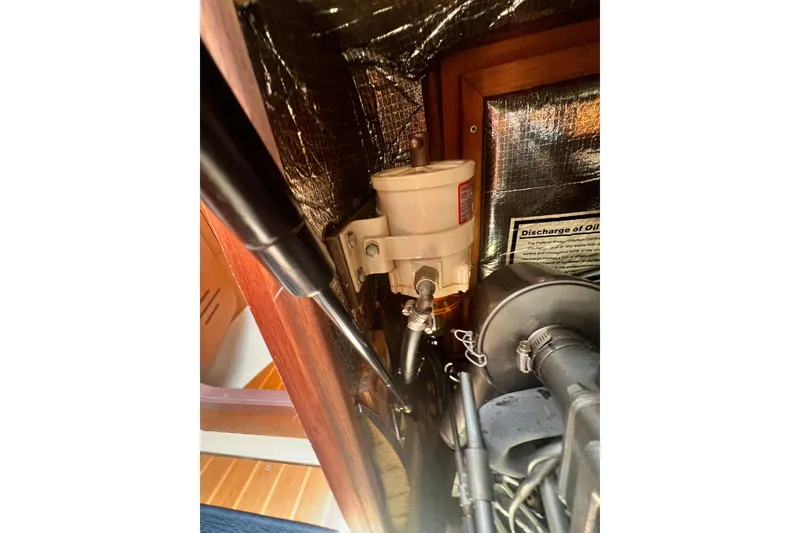 Slide: The Image of Engine compartment of a 1999 Hunter 380 sailboat, showing fuel filter and discharge notice. - 86