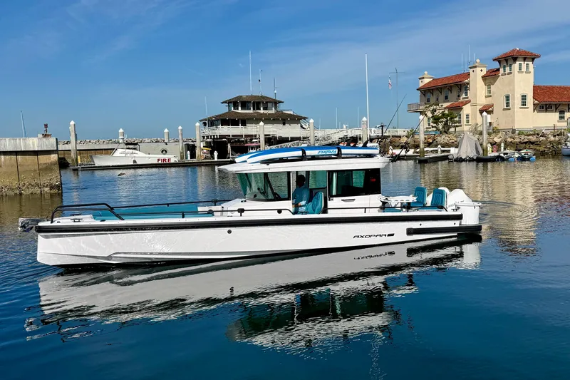 Slide: The Image of 2021 Axopar Brabus 28 Cabin boat docked in a scenic marina setting. - 1