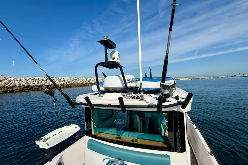 Slide: The Image of 2021 Axopar Brabus 28 Cabin boat with fishing rods, navigating calm waters. - 17