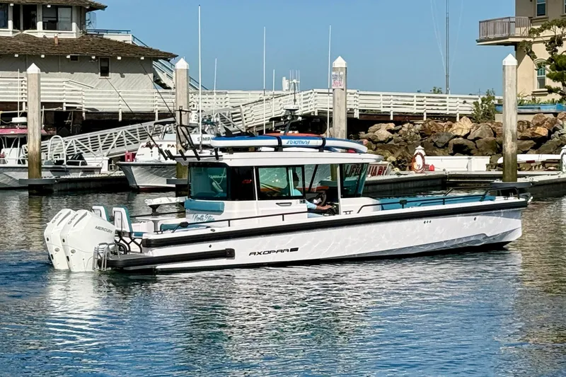 Slide: The Image of 2021 Axopar Brabus 28 Cabin boat docked in a marina, showcasing sleek design and powerful engines. - 4