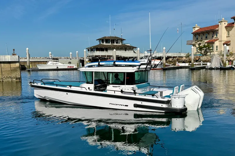 Slide: The Image of 2021 Axopar Brabus 28 Cabin boat docked in a marina under clear blue skies. - 6