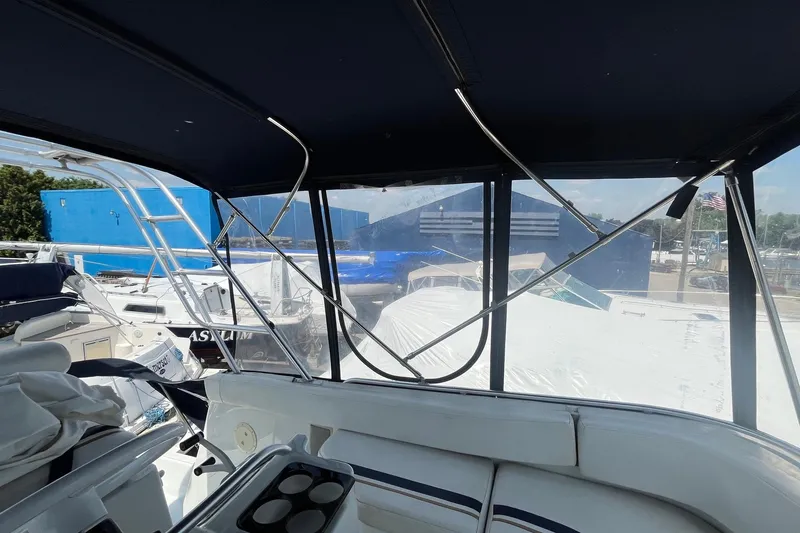 Slide: The Image of 1996 Mainship 40 Sedan Bridge interior view with covered seating and marina backdrop. - 25