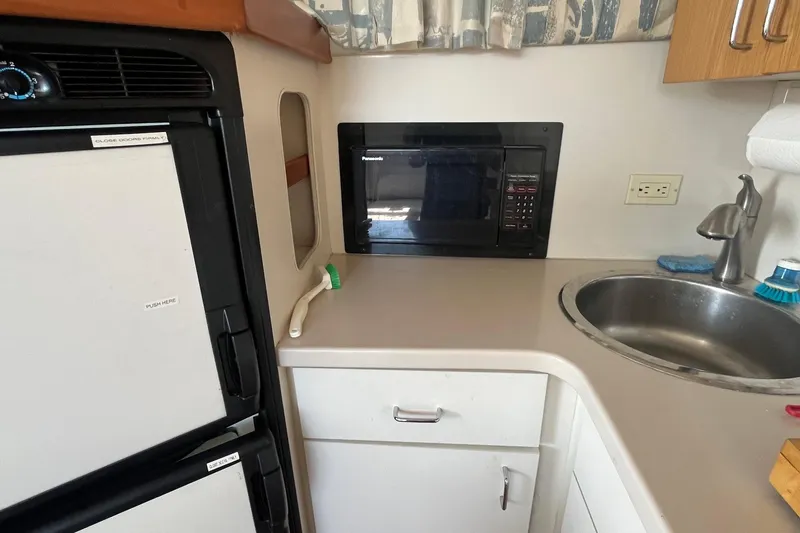 Slide: The Image of Compact kitchen area in a 1996 Mainship 40 Sedan Bridge with microwave and sink. - 30