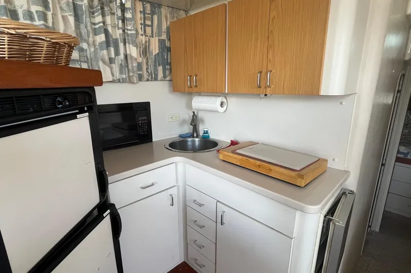 Slide: The Image of Compact kitchen area in a 1996 Mainship 40 Sedan Bridge yacht with sink and appliances. - 31