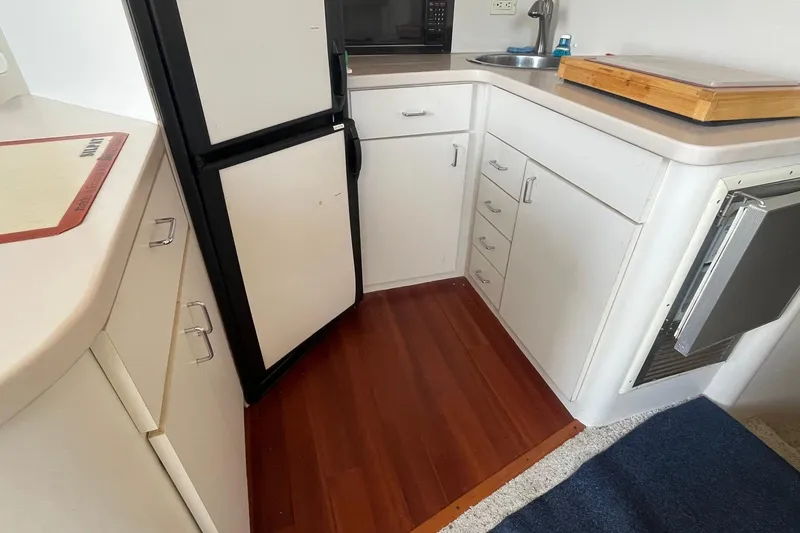 Slide: The Image of 1996 Mainship 40 Sedan Bridge kitchen with white cabinets and wood flooring. - 37