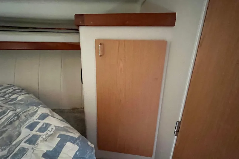 Slide: The Image of Interior of 1996 Mainship 40 Sedan Bridge, featuring wooden cabinetry and bedding. - 40