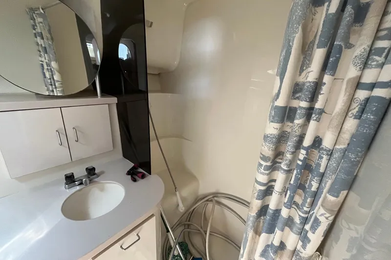 Slide: The Image of Bathroom interior of 1996 Mainship 40 Sedan Bridge with sink, mirror, and shower curtain. - 44