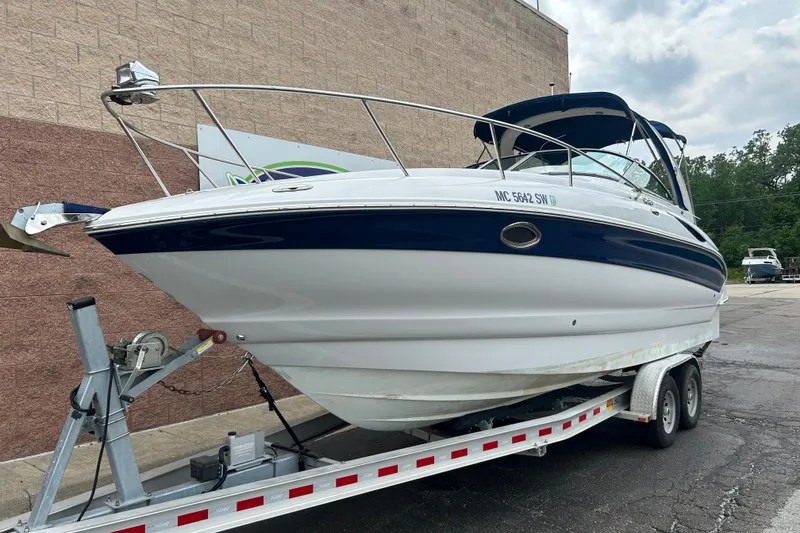 The Image of 2006 Crownline 270 CR boat on trailer, parked outdoors near a brick wall. - 0