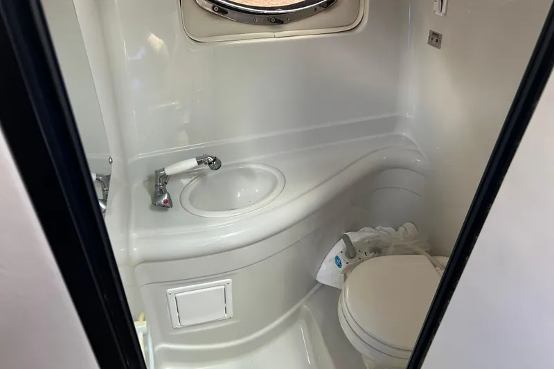 Slide: The Image of 2006 Crownline 270 CR boat bathroom with sink, toilet, and porthole window. - 29