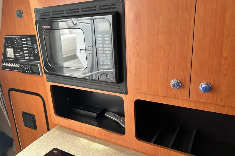 Slide: The Image of 2006 Crownline 270 CR interior with microwave, control panel, and wooden cabinetry. - 32
