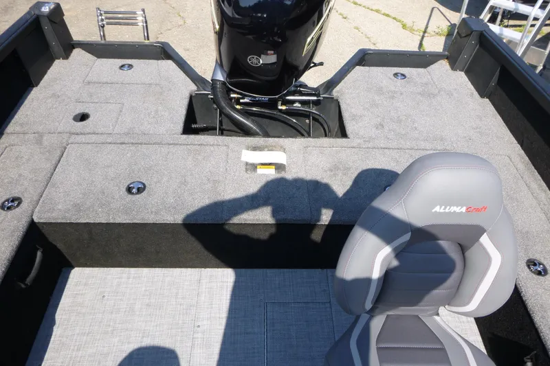 Slide: The Image of 2024 Alumacraft Competitor 185X Sport boat interior with seating and motor view. - 13