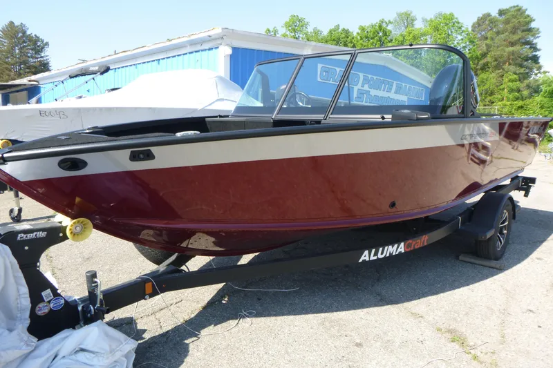 Slide: The Image of 2024 Alumacraft Competitor 185X Sport boat on trailer, red and white exterior. - 2