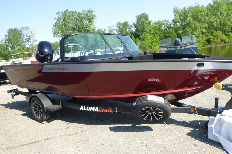 Slide: The Image of 2024 Alumacraft Competitor 185X Sport boat on trailer, parked outdoors. - 4