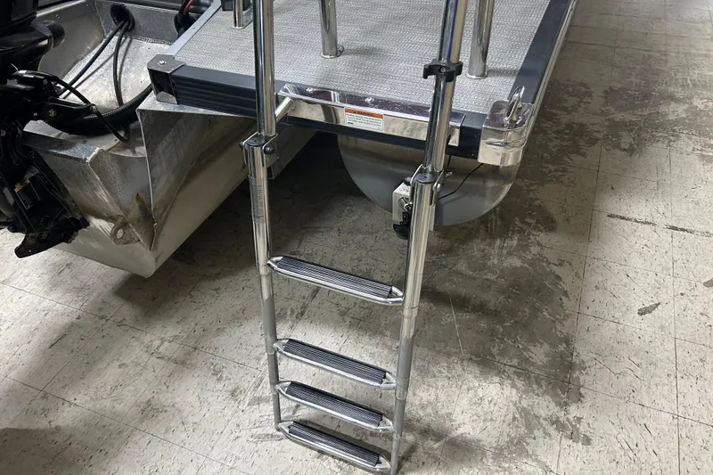 Slide: The Image of 2022 Manitou 25 Encore boat with a metal boarding ladder on a tiled floor. - 15