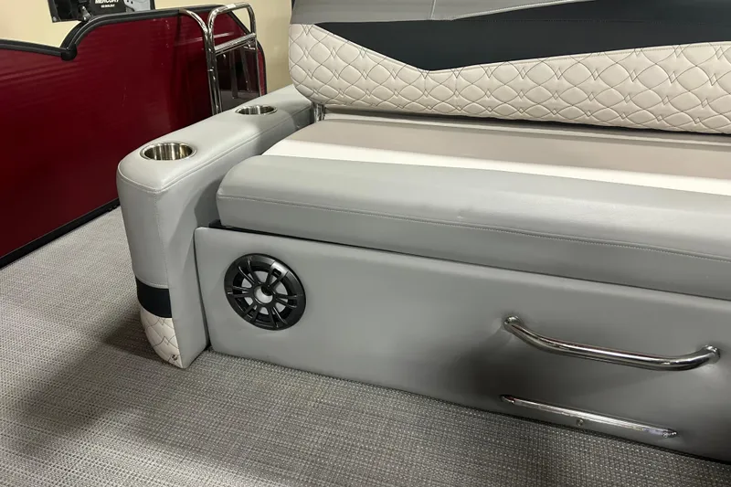 Slide: The Image of 2022 Manitou 25 Encore boat interior with gray seating, cup holders, and speaker. - 23