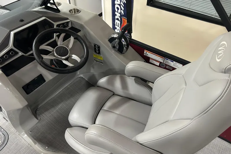 Slide: The Image of 2022 Manitou 25 Encore boat interior with steering wheel and captain's chair. - 24