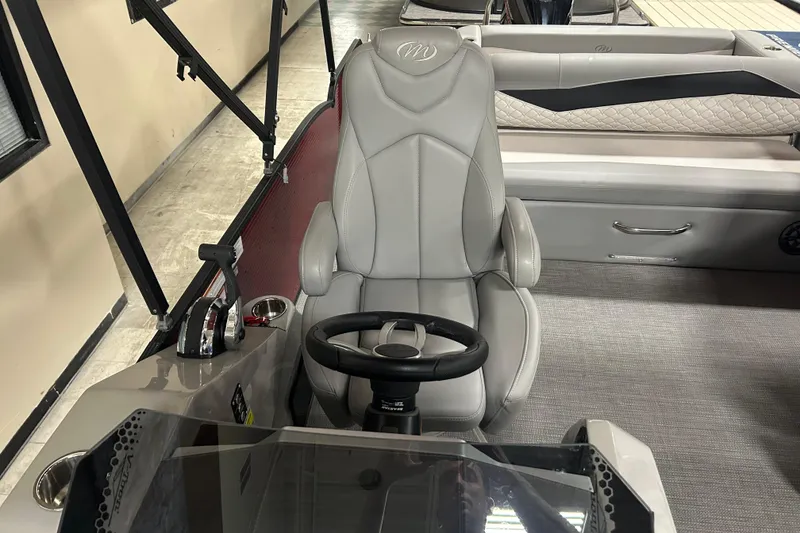 Slide: The Image of 2022 Manitou 25 Encore boat interior with gray captain's chair and steering wheel. - 36