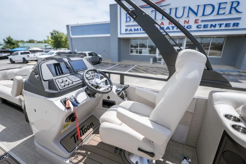 Slide: The Image of Interior of 2026 JC Sporttoon 26TT boat at dealership, featuring modern helm and seating. - 17
