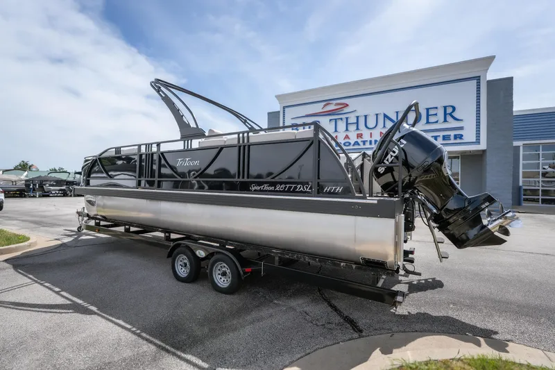 Slide: The Image of 2026 JC Sporttoon 26TT boat on trailer at dealership, featuring Suzuki outboard motor. - 7