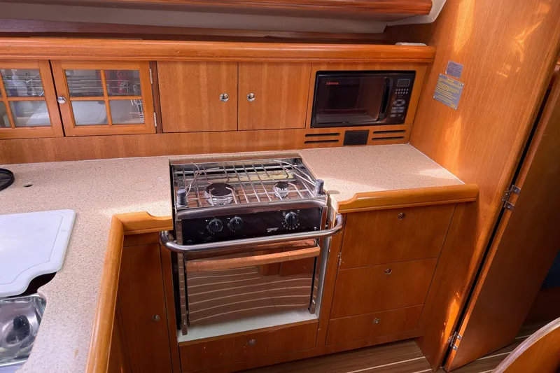 Slide: The Image of 2007 Hunter 38 yacht kitchen with stove, microwave, and wooden cabinetry. - 21