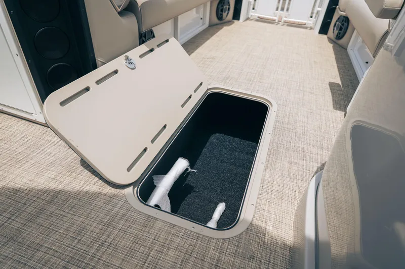 Slide: The Image of Open storage compartment on 2026 JC Sporttoon 26TT boat with beige interior. - 16