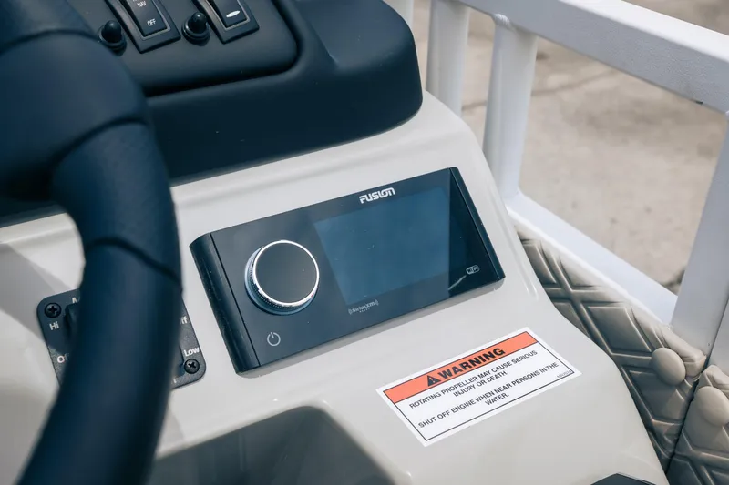 Slide: The Image of Control panel of 2026 JC Sporttoon 26TT boat with Fusion audio system and warning label. - 9