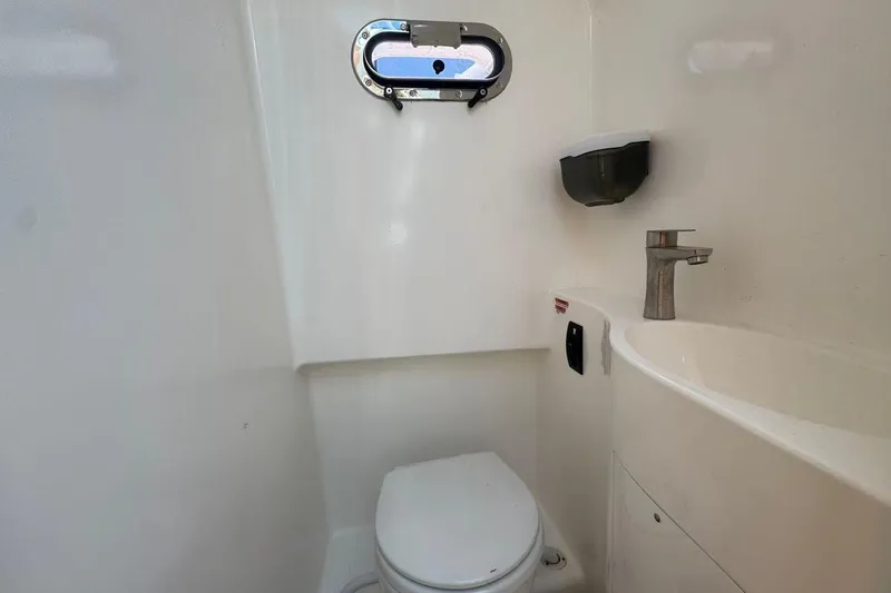 Slide: The Image of Compact bathroom in 2024 Bluewhale 3600 WA boat with toilet, sink, and porthole window. - 18