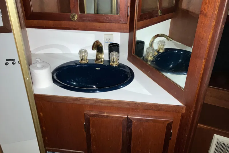 Slide: The Image of 1982 Trojan F-32 yacht bathroom with dark sink, wooden cabinetry, and mirrored wall. - 16