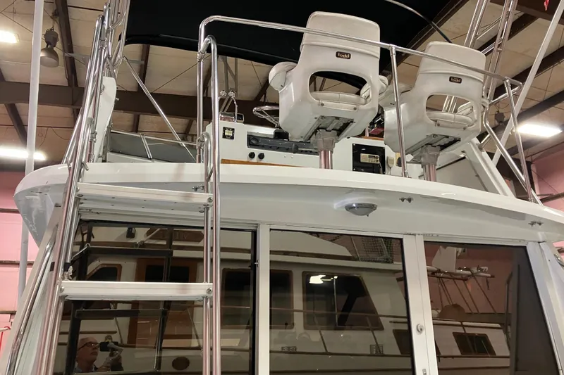 Slide: The Image of 1982 Trojan F-32 boat interior with helm chairs and ladder in a warehouse setting. - 3