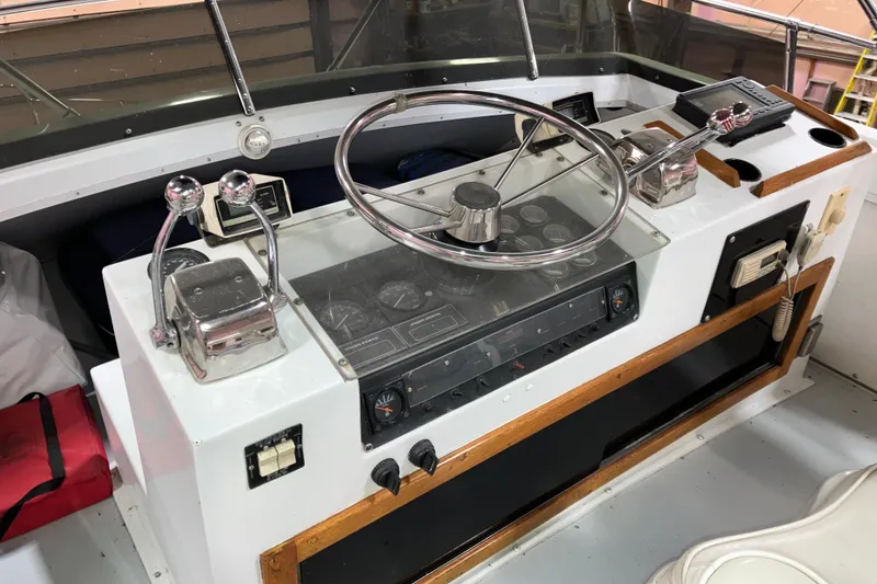 Slide: The Image of 1982 Trojan F-32 boat helm with steering wheel, dual throttle controls, and navigation instruments. - 18
