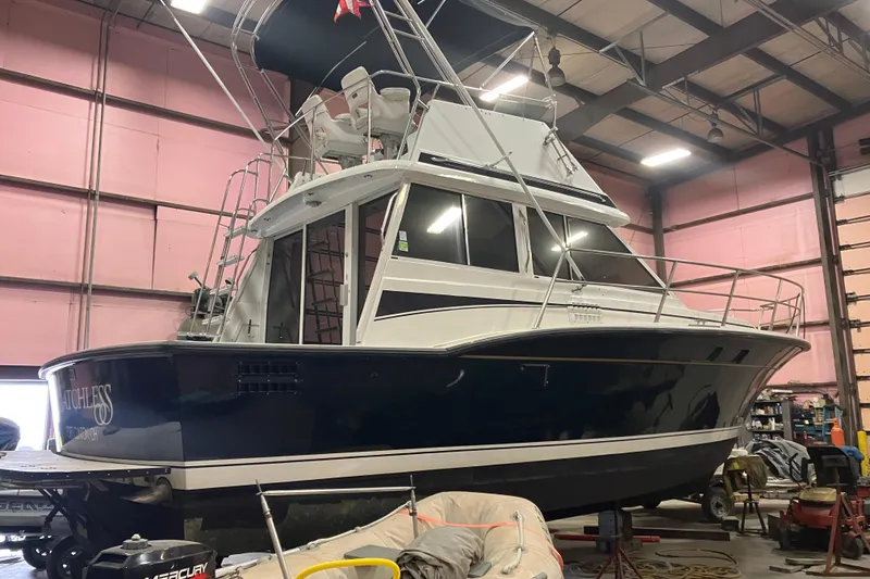 The Image of 1982 Trojan F-32 boat in a warehouse, elevated on supports, with visible equipment. - 0