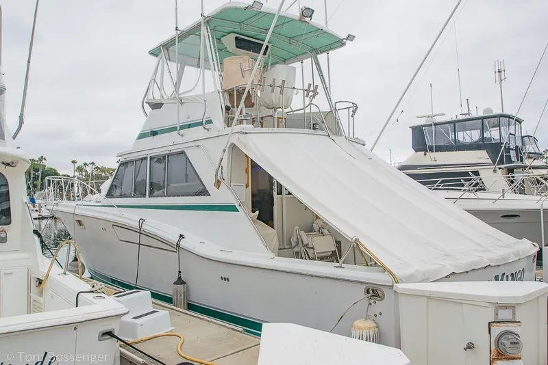 The Image of 1988 Chris-Craft 482 Convertible yacht docked at marina, featuring a covered deck area. - 1