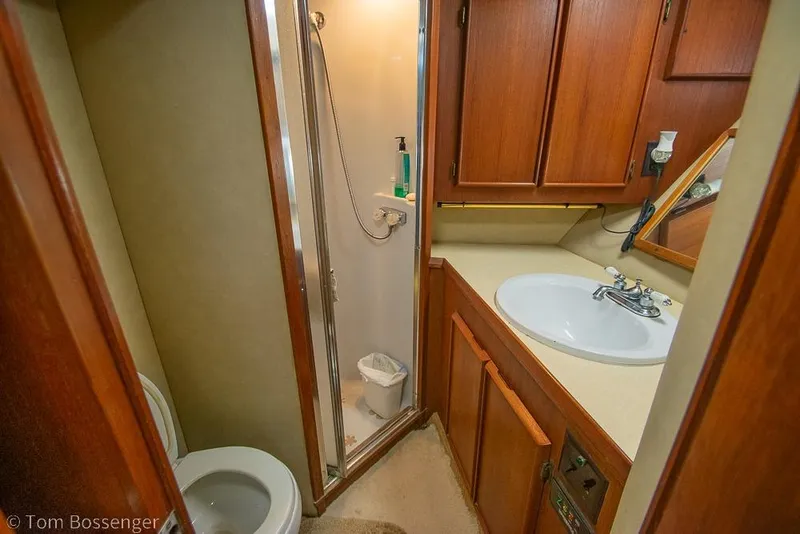 Slide: The Image of 1988 Chris-Craft 482 Convertible bathroom with shower, sink, and wooden cabinetry. - 16