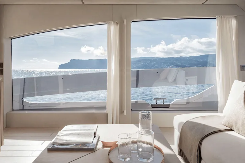 Slide: The Image of Interior view of a luxury yacht with large windows offering a view of the sea and coastline. - 17