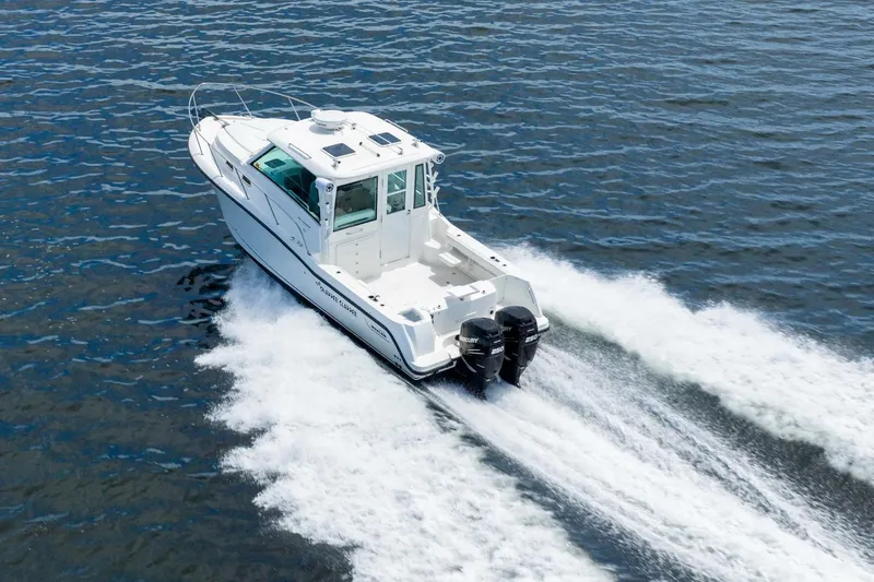 The Image of 2014 Boston Whaler 315 Conquest cruising on open water, rear view. - 0
