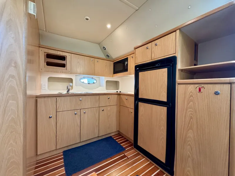 Slide: The Image of Interior of 1999 Tiara Yachts 4100 Open with wooden kitchen. - 4
