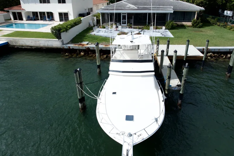 Slide: The Image of 1990 Viking 43 Convertible yacht docked near waterfront home with pool. - 1