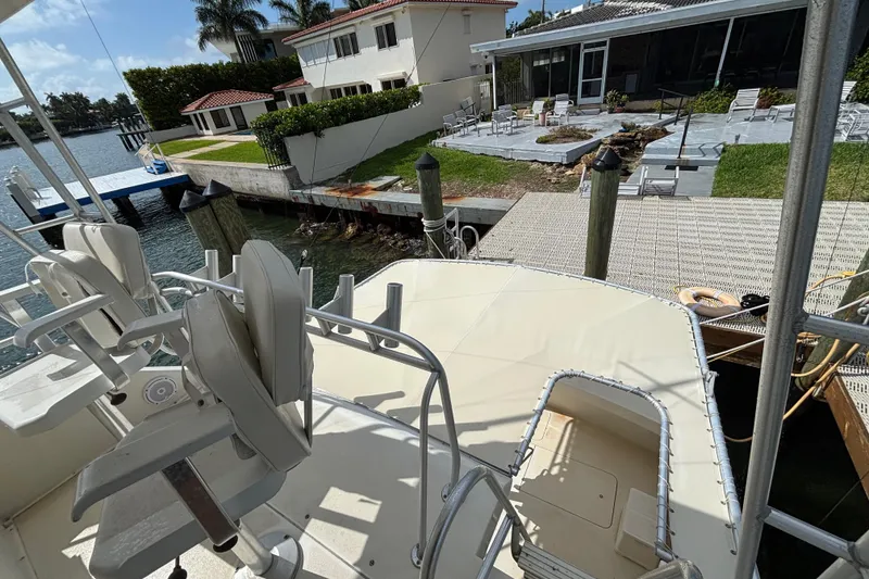 Slide: The Image of 1990 Viking 43 Convertible yacht docked near waterfront homes, featuring outdoor seating. - 13