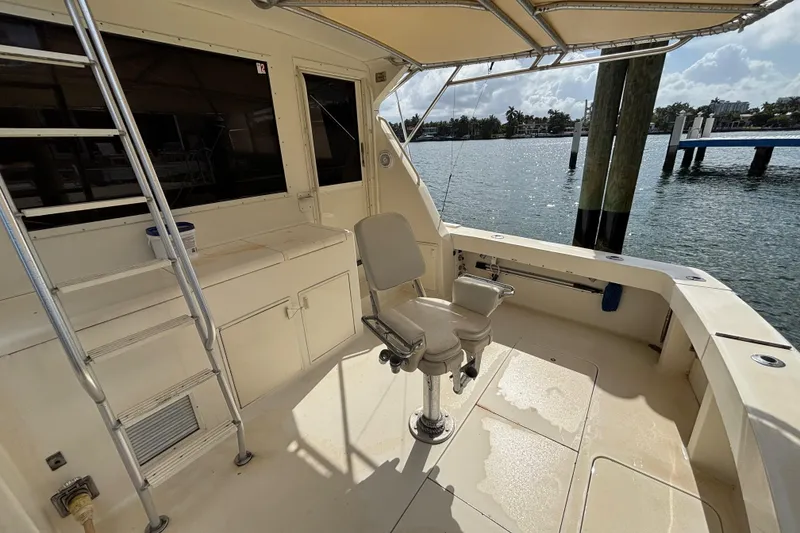 Slide: The Image of 1990 Viking 43 Convertible boat deck with fishing chair and ladder, docked by the water. - 16