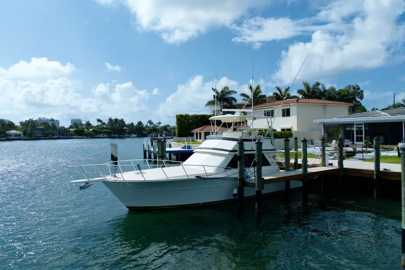 Slide: The Image of 1990 Viking 43 Convertible yacht docked by waterfront homes under a clear blue sky. - 3