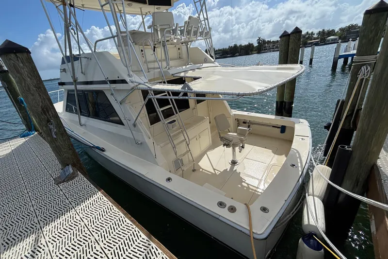 Slide: The Image of 1990 Viking 43 Convertible yacht docked, showcasing spacious deck and fishing chair. - 7