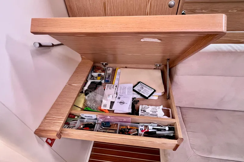 Slide: The Image of Open drawer on 2016 Hanse 455 yacht, containing various tools and documents. - 105