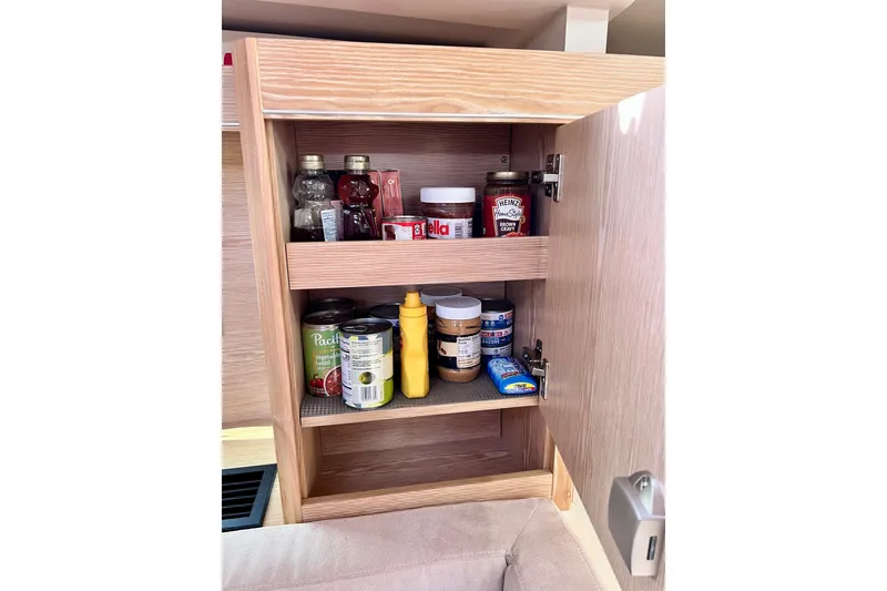 Slide: The Image of Wooden cabinet in 2016 Hanse 455 yacht, stocked with condiments and canned goods. - 129