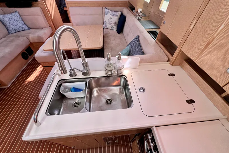 Slide: The Image of Modern kitchen area in a 2016 Hanse 455 yacht, featuring a double sink and cozy seating. - 135