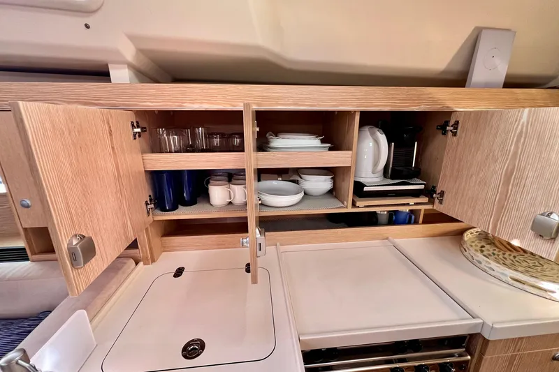Slide: The Image of Interior of 2016 Hanse 455 yacht kitchen with open cabinets displaying dishes and appliances. - 139