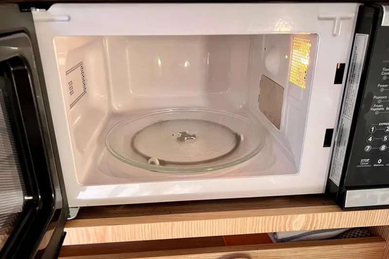 Slide: The Image of Open microwave oven with glass turntable on wooden shelf. - 141
