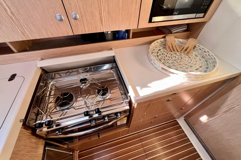 Slide: The Image of Modern kitchen in 2016 Hanse 455 yacht with stove, microwave, and wooden cabinetry. - 142
