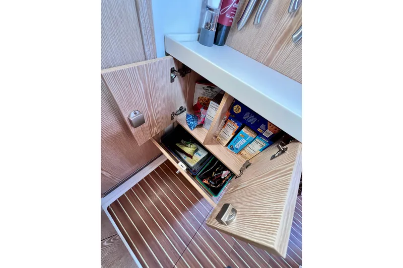 Slide: The Image of Open cabinet in 2016 Hanse 455 yacht, showcasing organized pantry items and wooden interior. - 151