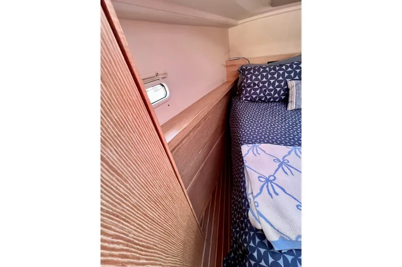 Slide: The Image of Interior cabin of 2016 Hanse 455 yacht with patterned bedding and wooden paneling. - 154