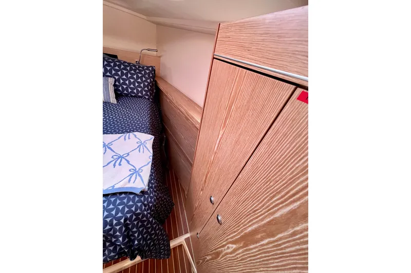 Slide: The Image of Cozy cabin interior of 2016 Hanse 455 yacht with wooden cabinetry and patterned bedding. - 159